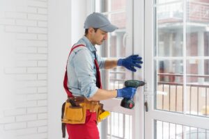 A man straightens a plastic window or door with a screwdriver.